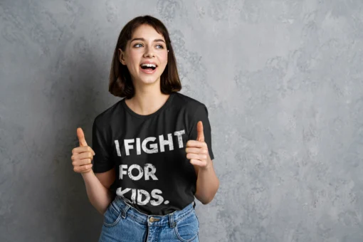 I Fight For Kids black t-shirt with woman wearing giving a thumbs up.